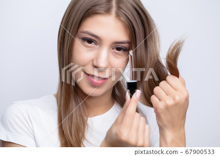 woman with beautiful hair, applies vitamins for hair growth 67900533