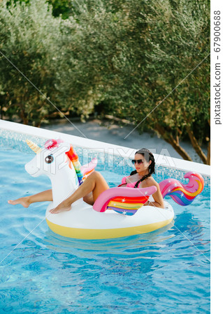 woman relax on inflatable pool toy unicorn in swimming pool woman relax on inflatable pool toy unicorn in swimming pool 67900688