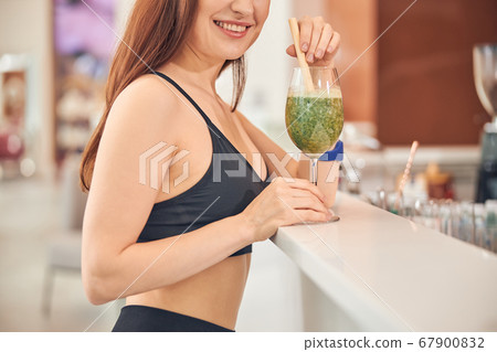 Pleased Caucasian woman with a glass of smoothie Pleased Caucasian woman with a glass of smoothie 67900832