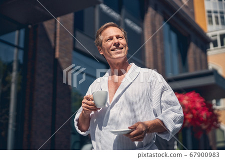 Cheerful man in bathrobe standing on the street Cheerful man in bathrobe standing on the street 67900983