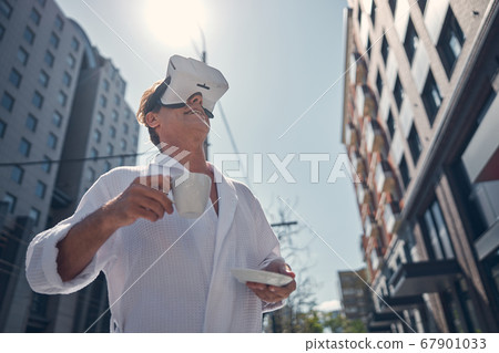 Joyful man in bathrobe using VR headset outdoors Joyful man in bathrobe using VR headset outdoors 67901033