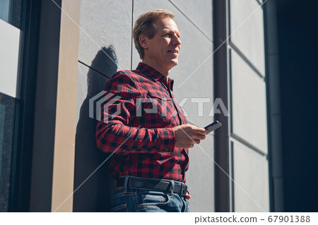 Handsome joyful man using smartphone outdoors on sunny day Handsome joyful man using smartphone outdoors on sunny day 67901388