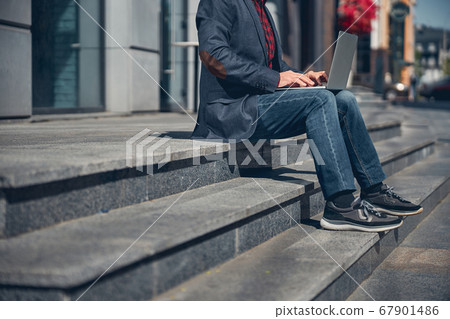 Stylish man using modern laptop on the street Stylish man using modern laptop on the street 67901486