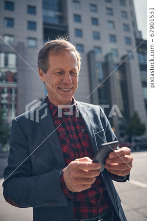Handsome joyful man using smartphone on the street 67901531