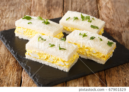 Egg salad tucked between slices of white bread, Egg salad tucked between slices of white bread, 67901829