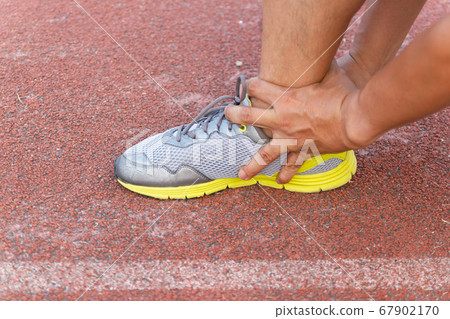 Sports Man Runner with injured ankle while training in the Stadium 67902170