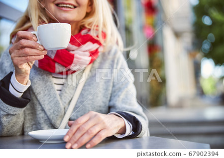 Relaxing lady sitting at the terrace with white mug 67902394