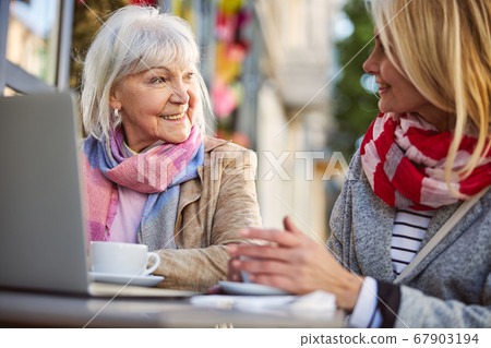 Conversation of two beautiful women in street cafe Conversation of two beautiful women in street cafe 67903194