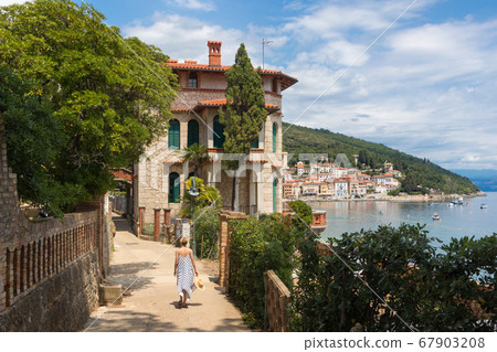 Female tourist walking along Adriatic sea coast relaxing on vacation in Moscenicka Draga, Istria, Croatia. 67903208