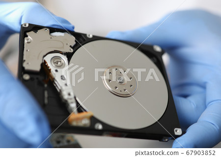 Gloved master holds hard drive away from computer. 67903852