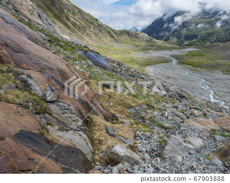 Summer view of alpine mountain valley with winding stream and glacial lake, Sulzenauferner Glacier, Stubai Alps, Austria Summer view of alpine mountain valley with winding stream and glacial lake, Sulzenauferner Glacier, Stubai Alps, Austria 67903888