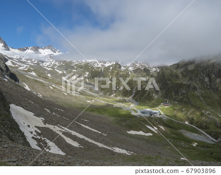 Aerial view on snow spotted mountains with Mittelstation of Stubaier Gletscher cable car station and Dresdner Huette alpine hut. Tyrol, Austria Summer sunny day 67903896