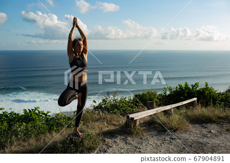 Young woman practicing yoga outdoors 67904891