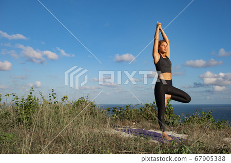 Young woman practicing yoga outdoors 67905388