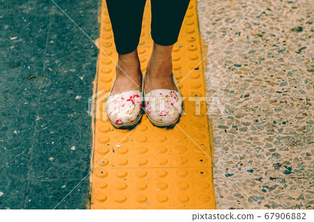 Woman wearing doll shoes standing on a yellow line showing concept of social distancing, isolation, the new normal lifestyle and travel during the covid-19 pandemic 67906882