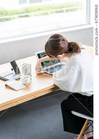 Young woman setting a desk fan during telework [Cool Biz] 67909068