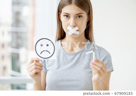 Stop smoking, a woman with a sealed mouth holding a broken cigarette 67909183