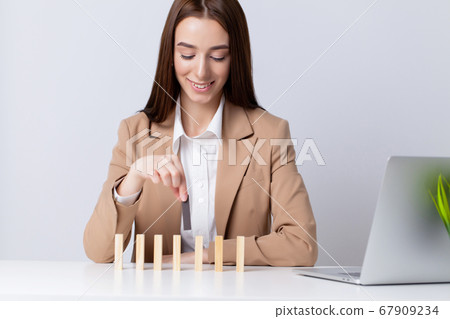 Beautiful young woman makes wooden cubes on the desk in the office 67909234