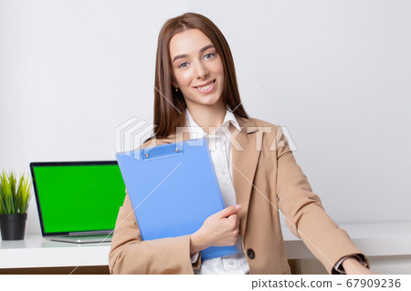 Beautiful young woman in a jacket working in the office at the desk 67909236
