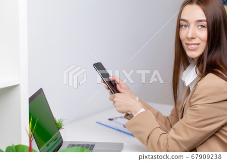 Beautiful young woman in a jacket working in the office at the desk 67909238