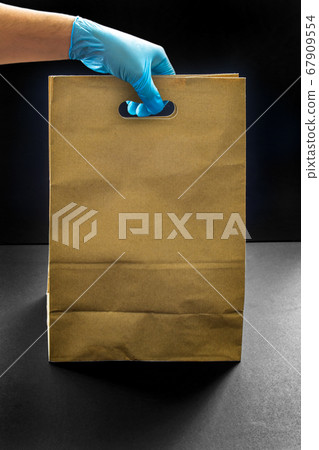 A person wearing gloves holding a shopping brown 67909554