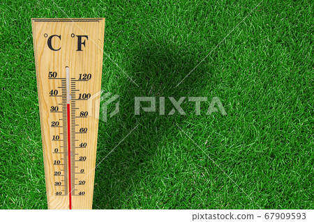 Wooden weather thermometer measurement on a green Wooden weather thermometer measurement on a green 67909593