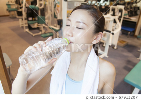 Woman exercising and drinking water Woman exercising and drinking water 67913207
