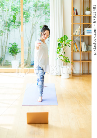 Young woman doing online yoga at home Young woman doing online yoga at home 67913493