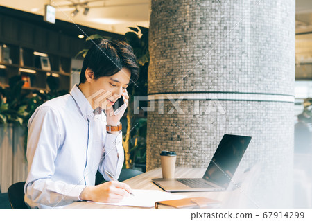 A man looking at a computer while calling A man looking at a computer while calling 67914299