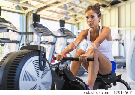 Workout woman cross training exercising cardio using rowing machine in fitness gym. Asian girl working out 67914567
