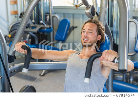 Man doing chest exercises on vertical bench press machine 67914574