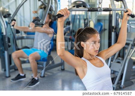 Fitness girl working out shoulders and upper back at lat pulldown machine, strength training at gym 67914587