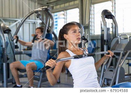Fitness Asian woman working out shoulder pull down at gym. Girl strength training using lat pulldown machine 67914588