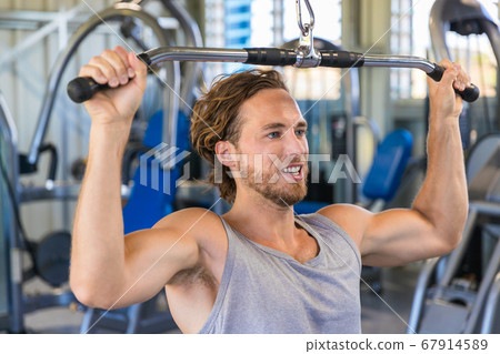 Shoulder pull down machine. Fitness man working out lat pulldown training at gym. Upper body strength exercise for the upper back 67914589