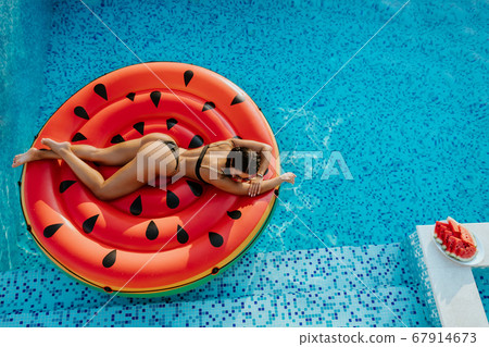 woman relax in swimming pool on inflatable pool toy at summer day woman relax in swimming pool on inflatable pool toy at summer day 67914673