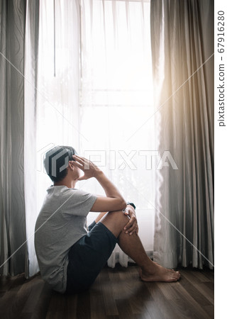 Sad and depressed young male sitting on the floor in the living room looking outside the doors,sad mood,feel tired, lonely and unhappy concept. Selective focus. Sad and depressed young male sitting on the floor in the living room looking outside the doors,sad mood,feel tired, lonely and unhappy concept. Selective focus. 67916280