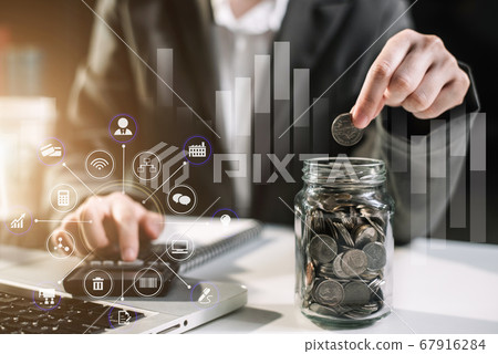 Businesswoman hand puting coins in glass for saving money at home office. concept finance and accounting in the home. Businesswoman hand puting coins in glass for saving money at home office. concept finance and accounting in the home. 67916284
