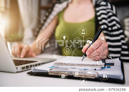 Female businessman use a laptop computer and take notes in the notebook at the home office desk in the morning. Female businessman use a laptop computer and take notes in the notebook at the home office desk in the morning. 67916286