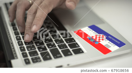 Man pays online with plastic bank card with printed flag of Croatia. Fictional numbers 67918656