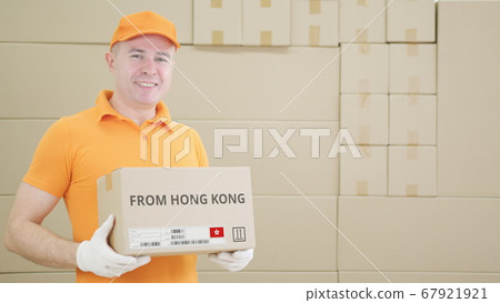Warehouse worker holds cardboard box with printed FROM HONG KONG text on it Warehouse worker holds cardboard box with printed FROM HONG KONG text on it 67921921