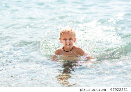 Happy little boy playing in the waves at the 67922281