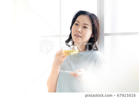 Middle women who enjoy herbal tea indoors [Prevention of cold] 67923816