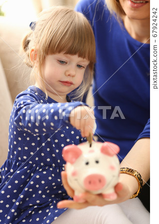 Child little girl arm putting coins into piggybank 67924242