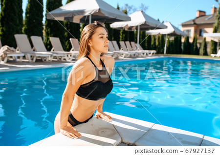 Sexy woman gets out of the water in pool outdoors 67927137