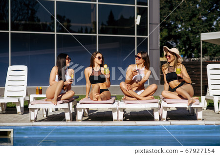 Pretty women in swimsuits sunbathing with coctails Pretty women in swimsuits sunbathing with coctails 67927154