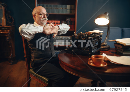 Elderly writer prepares to work on typewriter Elderly writer prepares to work on typewriter 67927245