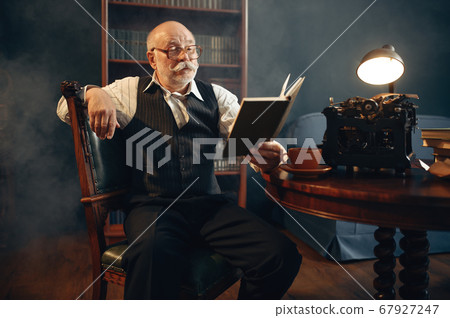 Elderly writer reads work at vintage typewriter Elderly writer reads work at vintage typewriter 67927247