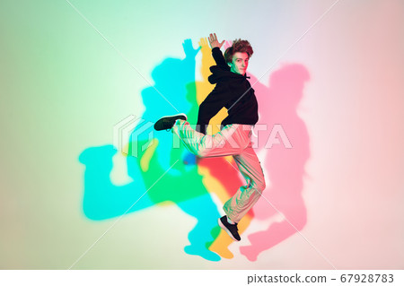 Young beautiful man dancing hip-hop, street style isolated on studio background in neon light 67928783