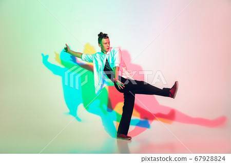 Young beautiful man dancing hip-hop, street style isolated on studio background in neon light Young beautiful man dancing hip-hop, street style isolated on studio background in neon light 67928824