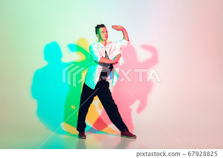 Young beautiful man dancing hip-hop, street style isolated on studio background in neon light Young beautiful man dancing hip-hop, street style isolated on studio background in neon light 67928825